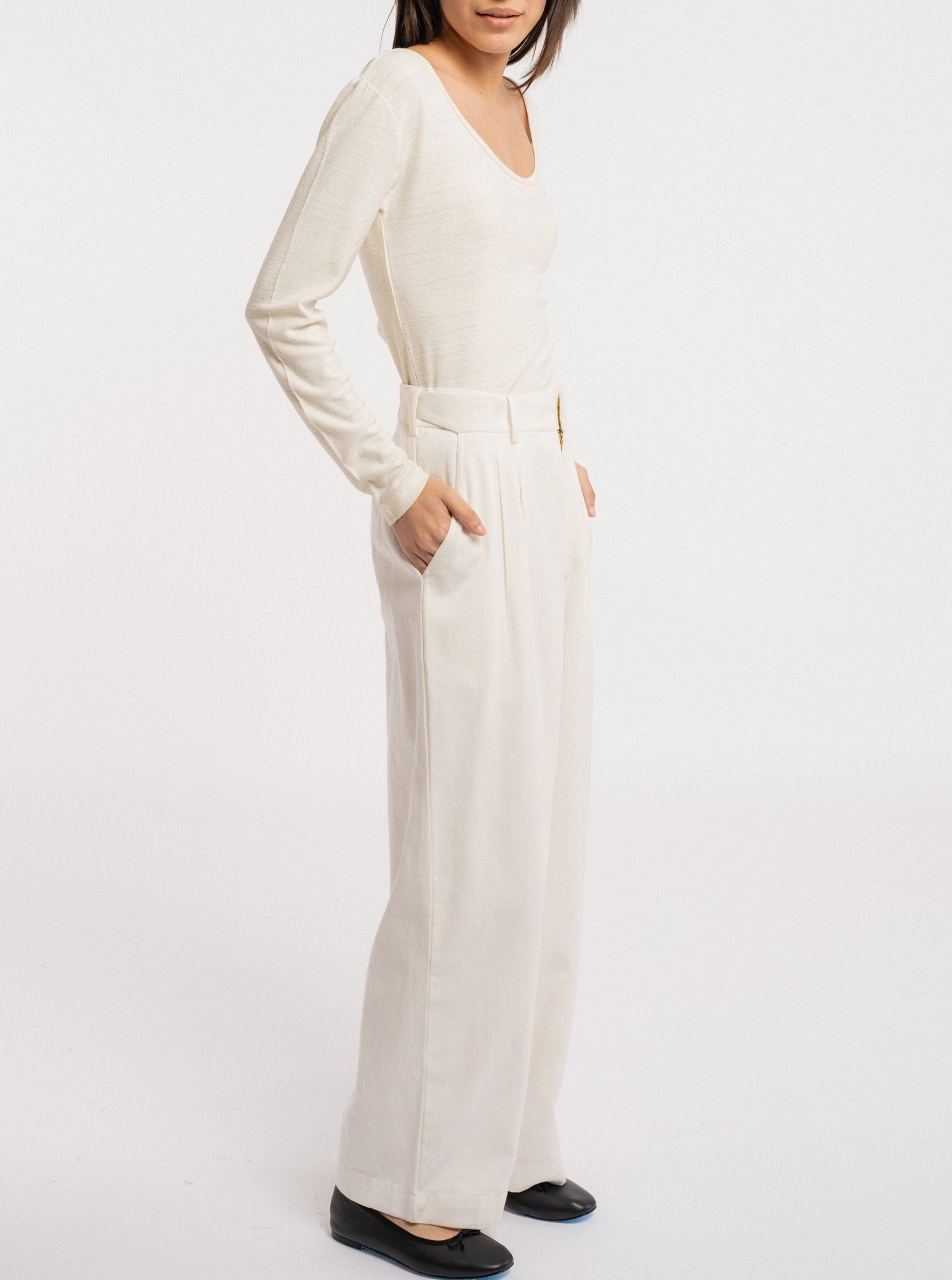 The model is wearing a white long-sleeved Scoop Neck Tee - Ivory made from silk noil, showcasing sustainability in its wide leg pants.