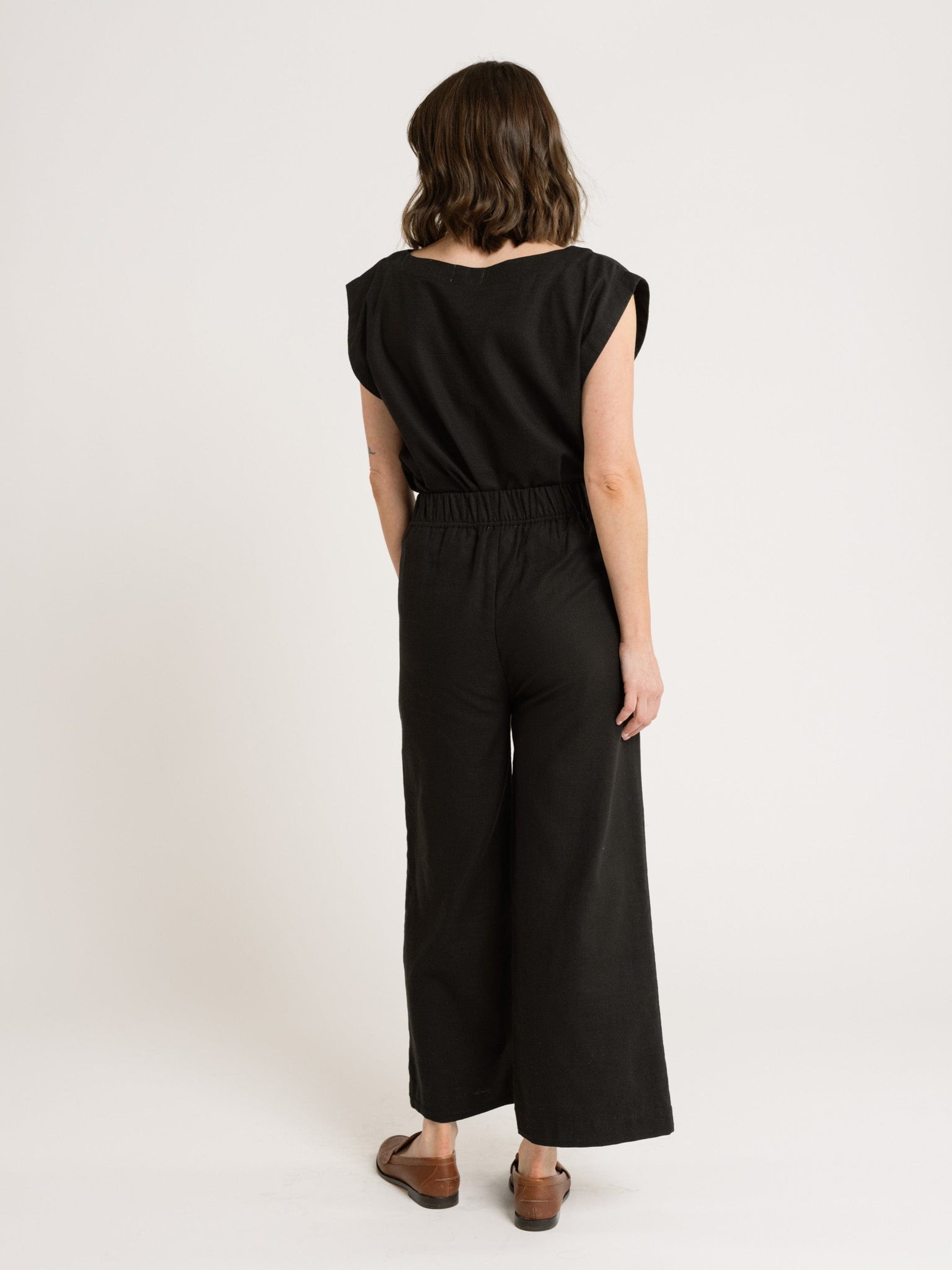 The back view of a woman wearing the Everyday Top - Black Cotton jumpsuit.