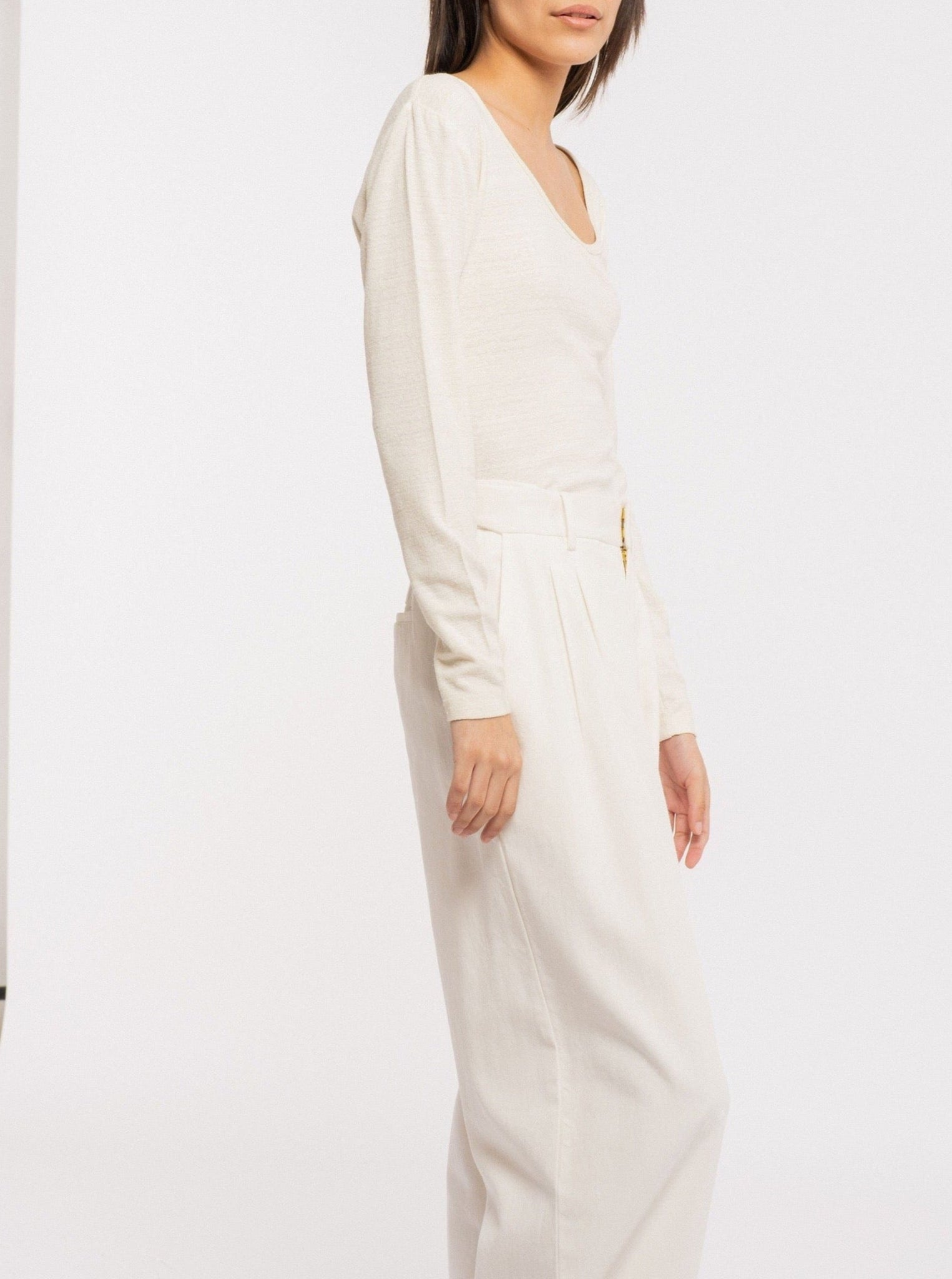 The model is wearing a white blouse with a Scoop Neck Tee - Ivory and wide leg pants made from sustainable silk noil.