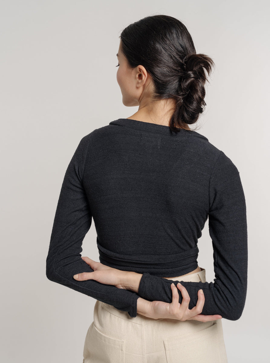 The back view of a woman wearing the Ballet Wrap Top - Black Silk Noil - Pre-order.