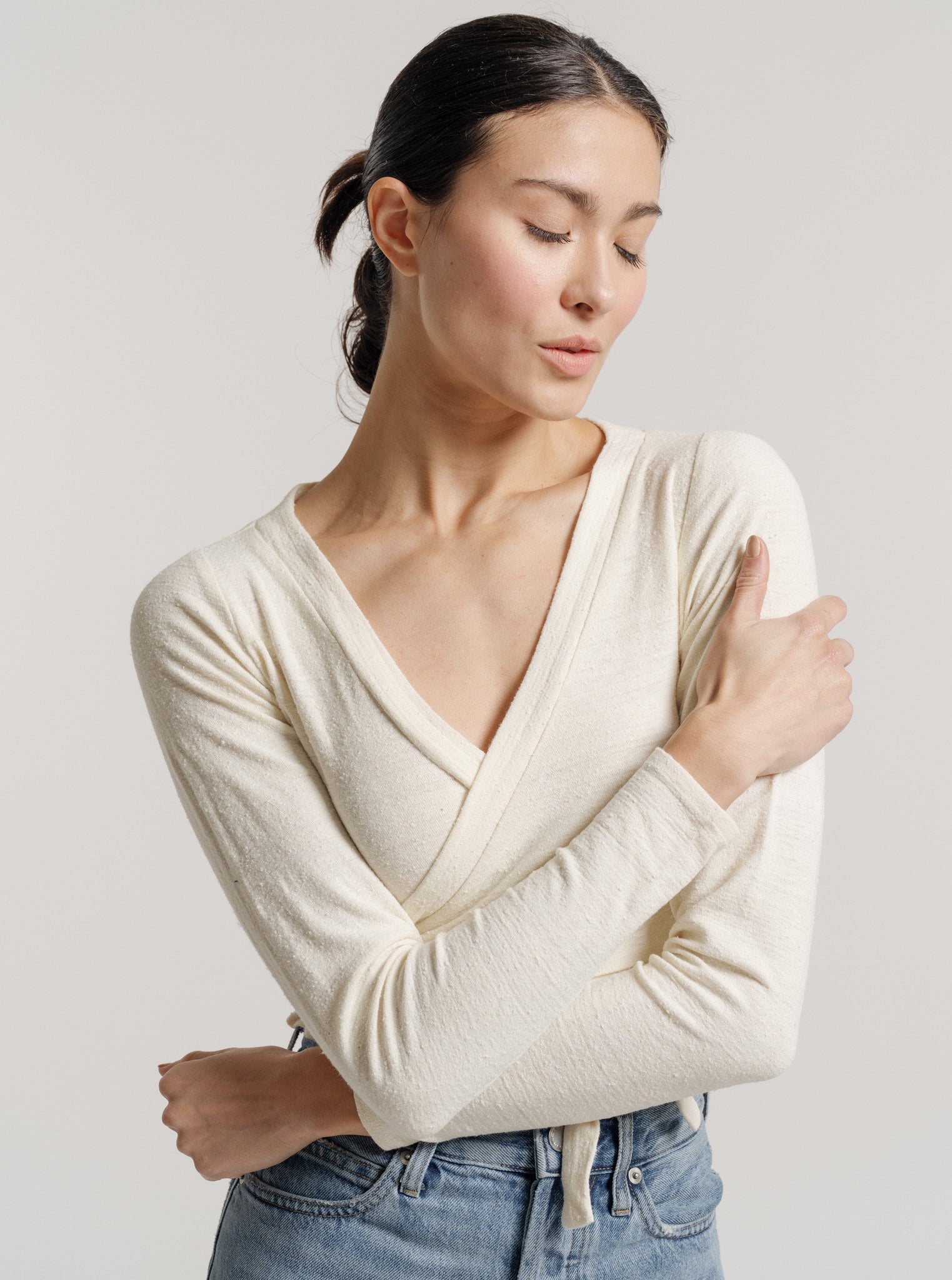 The model is wearing a Ballet Wrap Top - Ivory Silk Noil - Pre-order and jeans.
