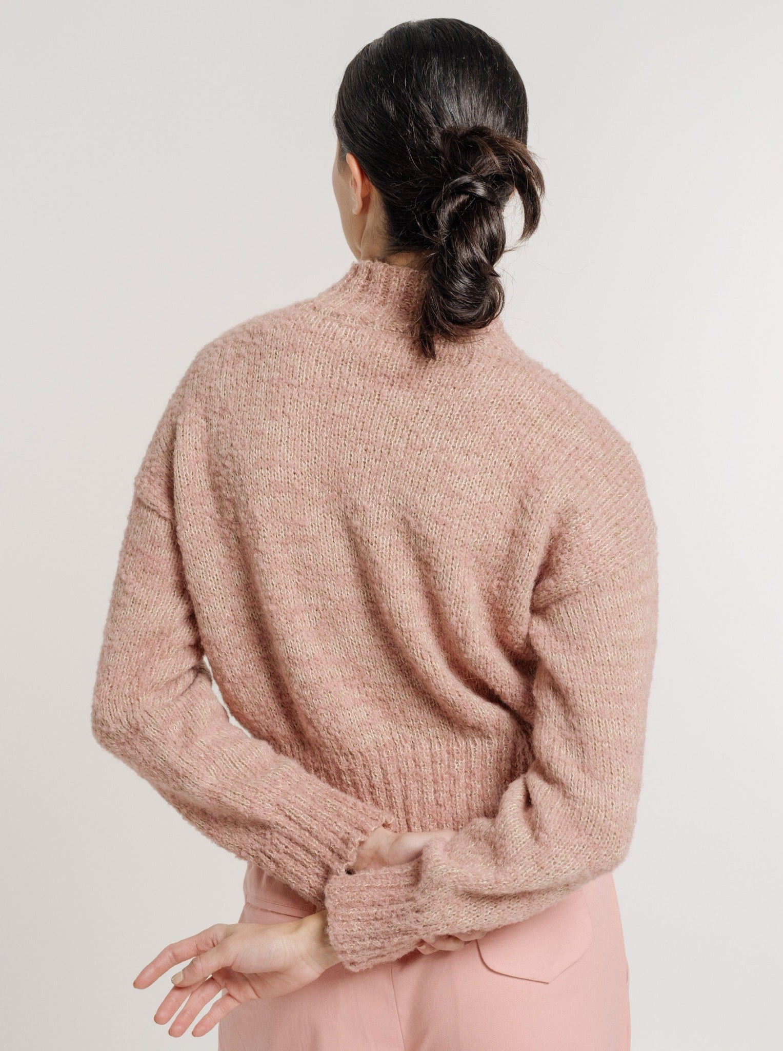 The back view of a woman wearing cozy high-waisted pants and the Claudia Sweater - Pincusion Pink.