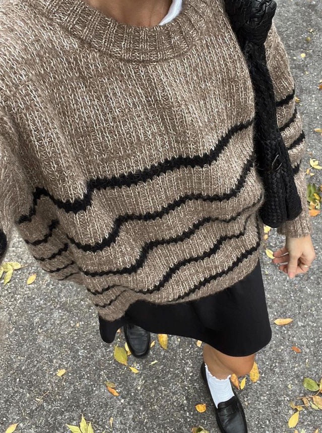 A woman is taking a selfie wearing the Field Sweater - Brown Stripe made of cozy knit.