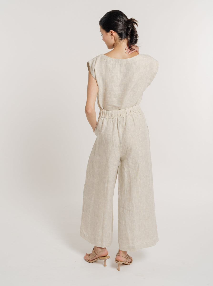 The back view of a woman wearing the Everyday Pant - Natural Linen jumpsuit.