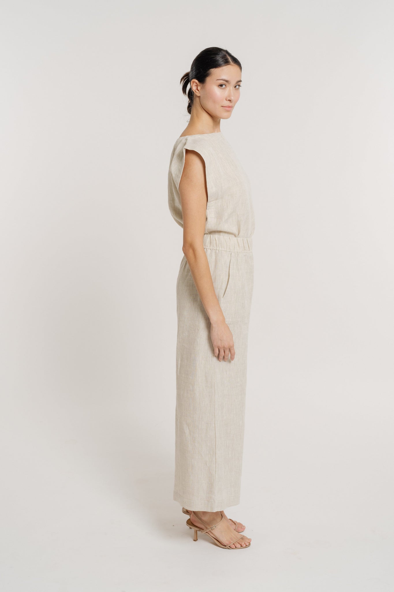 The model is wearing a beige Everyday Pant - Natural Linen made of organic linen fabric.