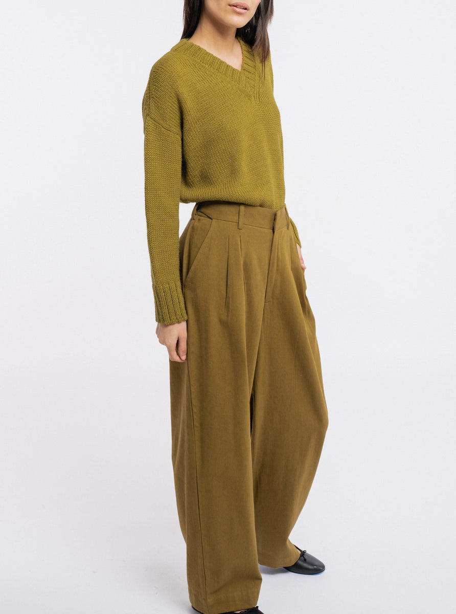 The model is wearing a green sweater made of organic cotton and Alfred Trouser - Olive for comfortability.