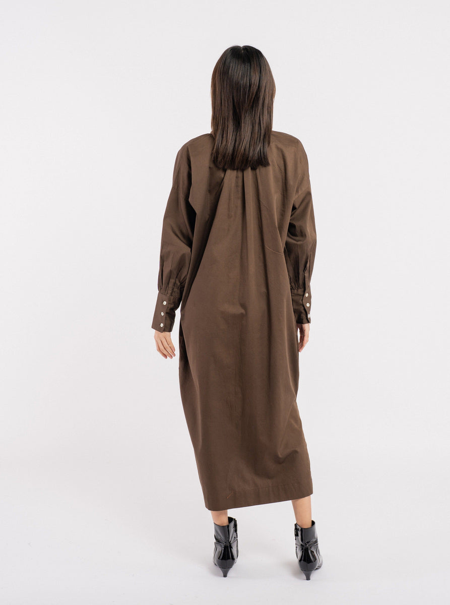 The back view of a woman wearing a Dolores Dress - Balsalt Brown - pre-order.