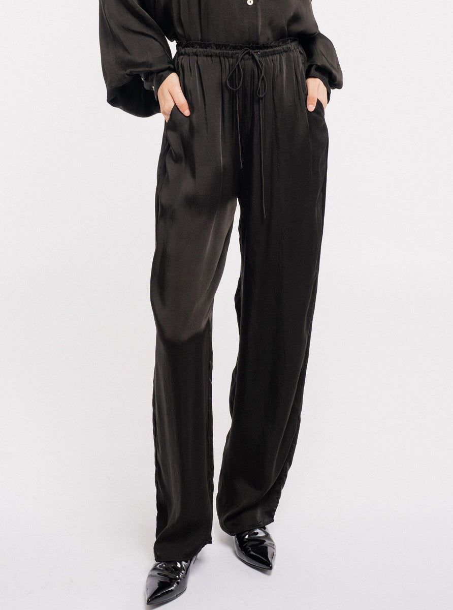 The model is wearing a Leonie Pant - Black jumpsuit.
