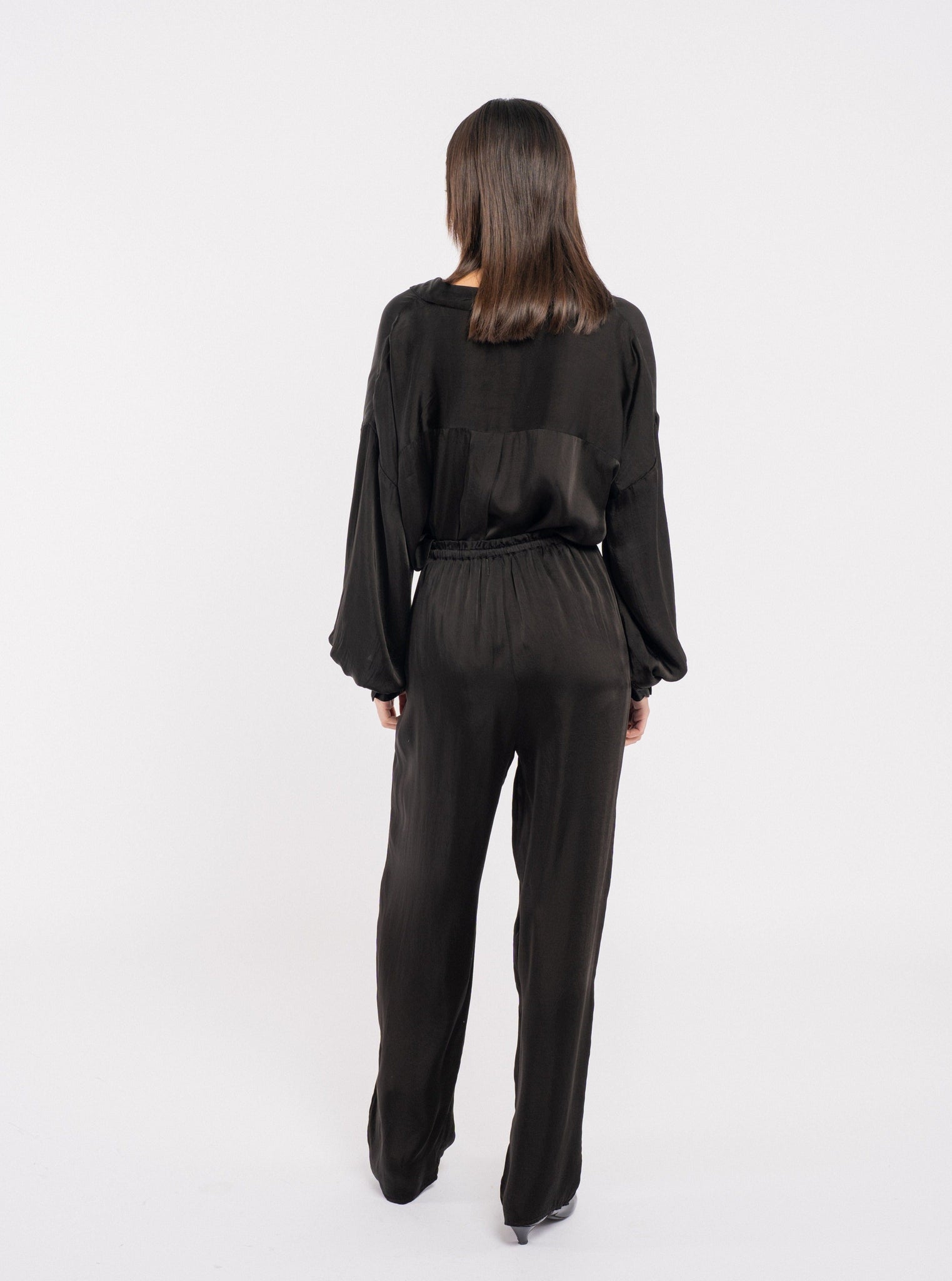 The back view of a woman wearing the Leonie Pant - Black, made from Bemberg cupro fabric.