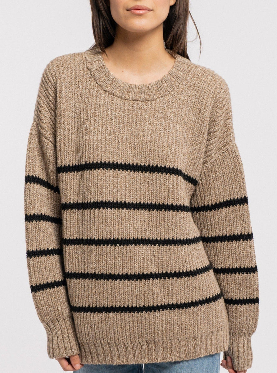 A woman wearing a cozy knit Field Sweater - Brown Stripe.