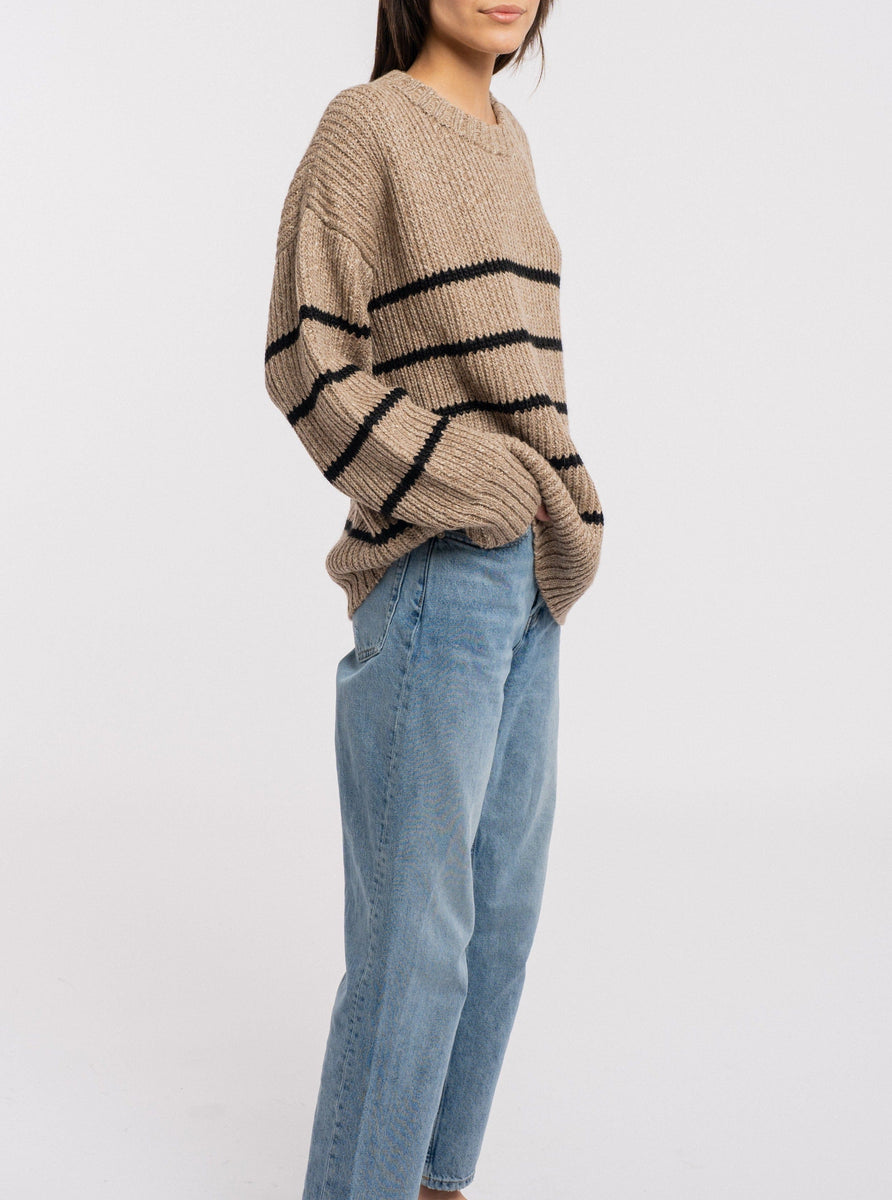 The model is wearing a cozy knit Field Sweater - Brown Stripe.