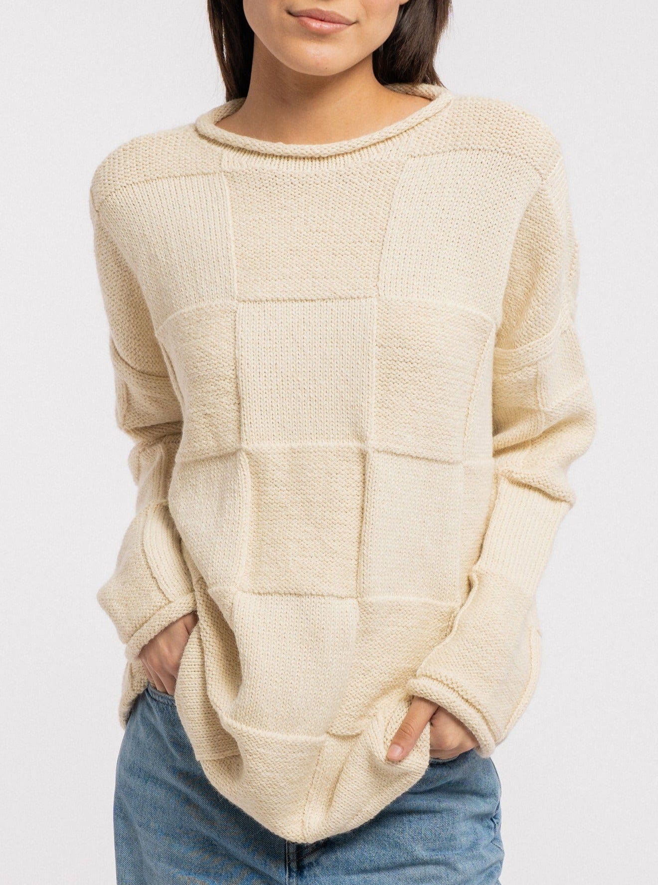 A cozy model wearing the Heritage Basketweave Sweater - Ivory.