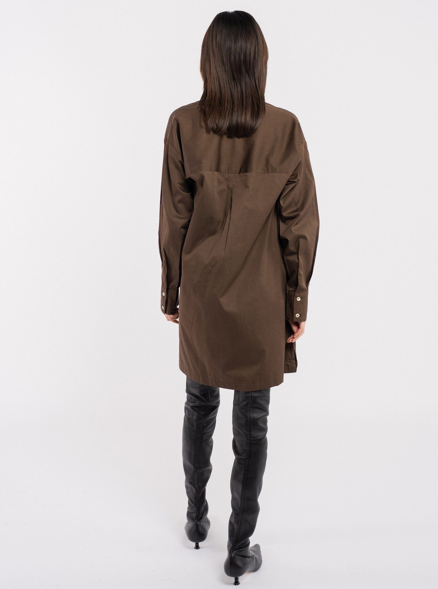 The back view of a woman wearing a Modern Tunic Dress - Basalt Brown and thigh high boots.