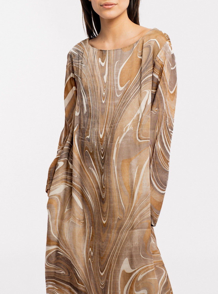 A woman wearing a Sparrow Dress - Hand Marble, a long fluid maxi length dress made of hand-marbled cupro.