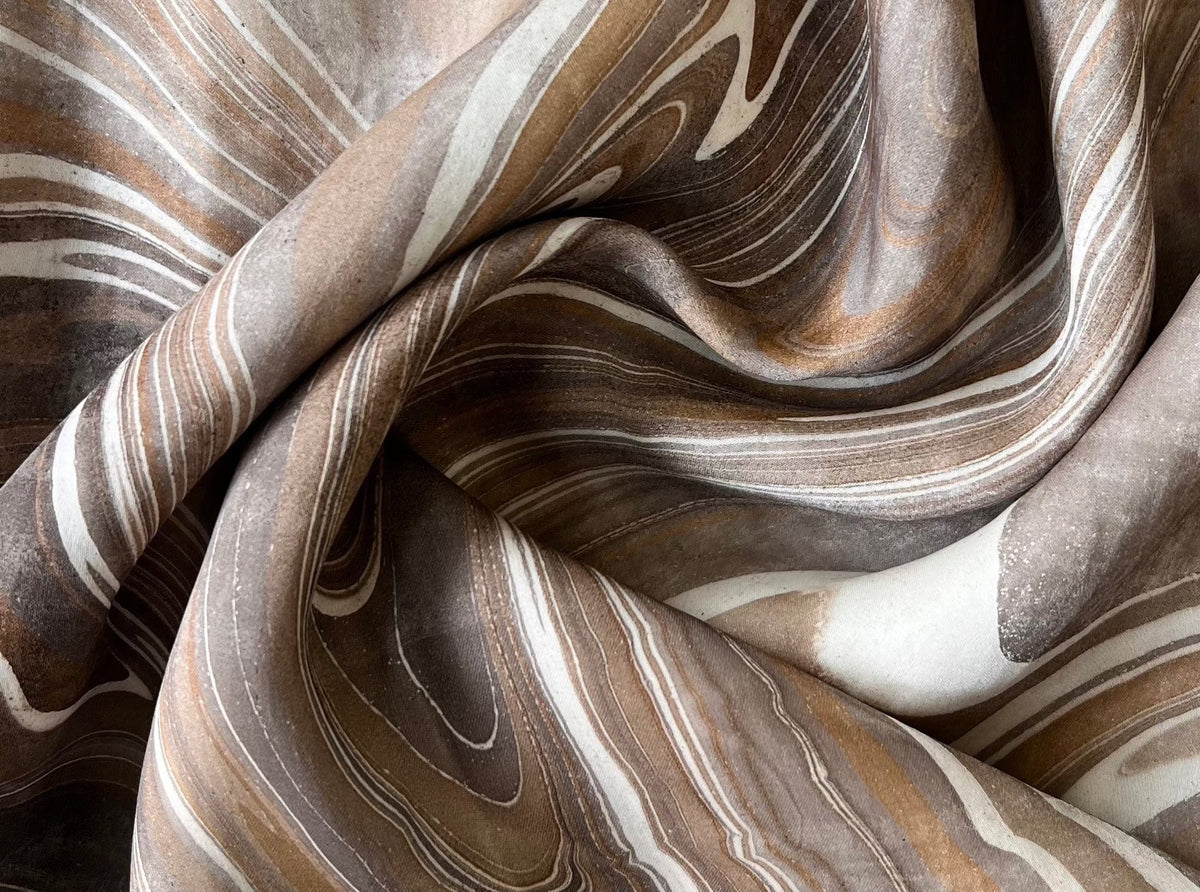 A close up of a brown and white marbled fabric, featuring the Sparrow Dress - Hand Marble.