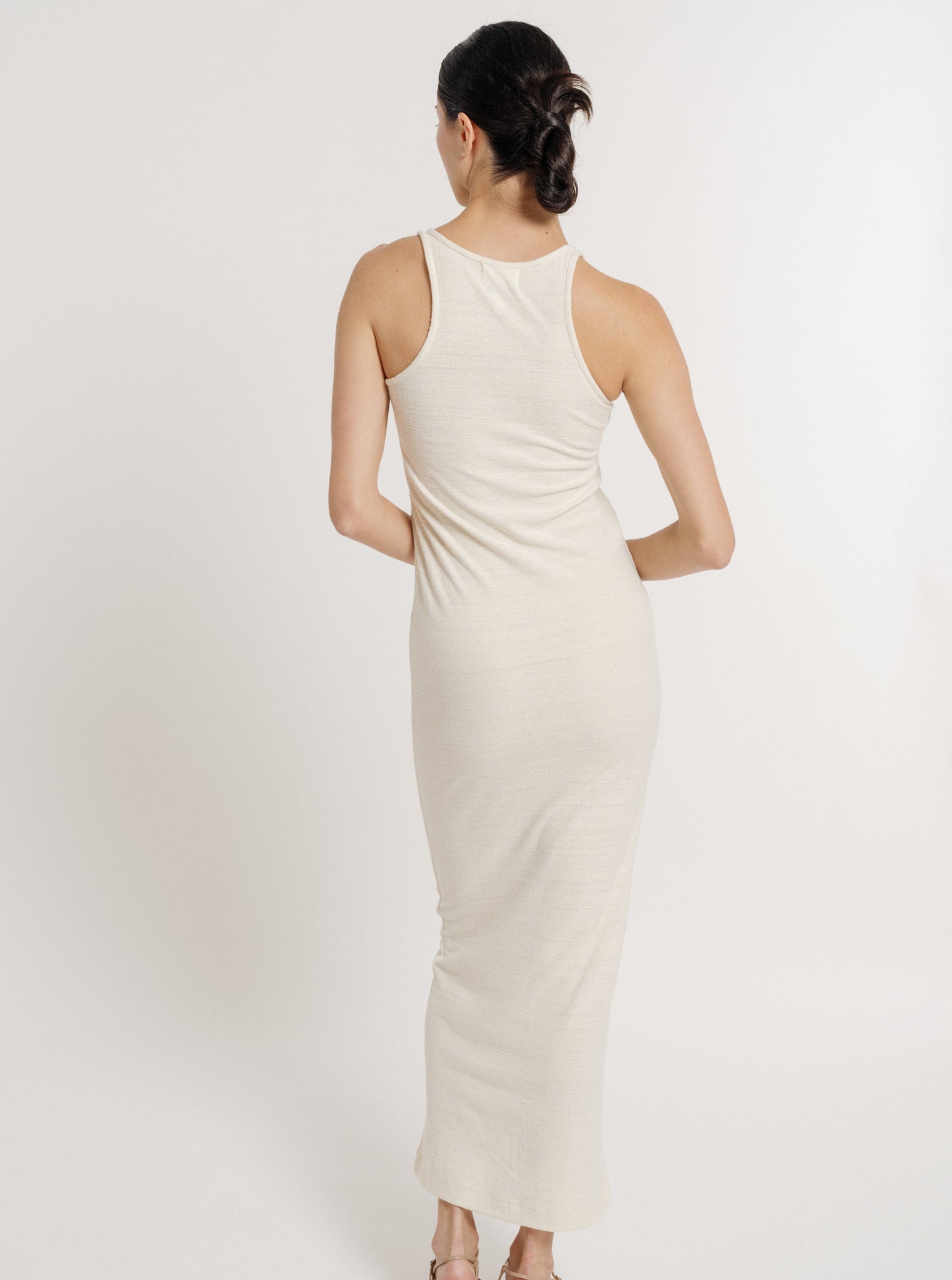 The back view of a woman wearing a pre-ordered Jersey Knit Tank Dress - Ivory Silk Noil, showcasing her individuality.