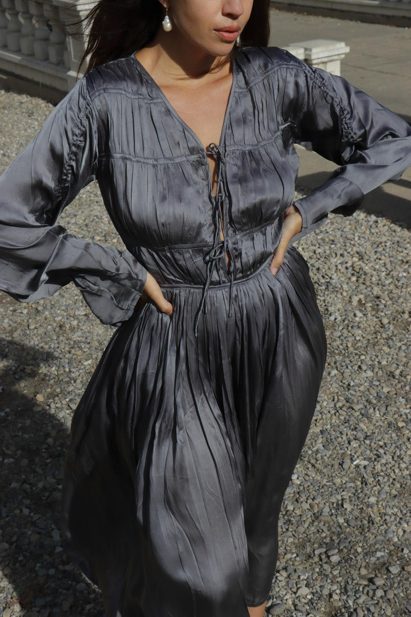 A woman is posing in an Iris Dress - Slate with adjustable sleeves and ruching detail.