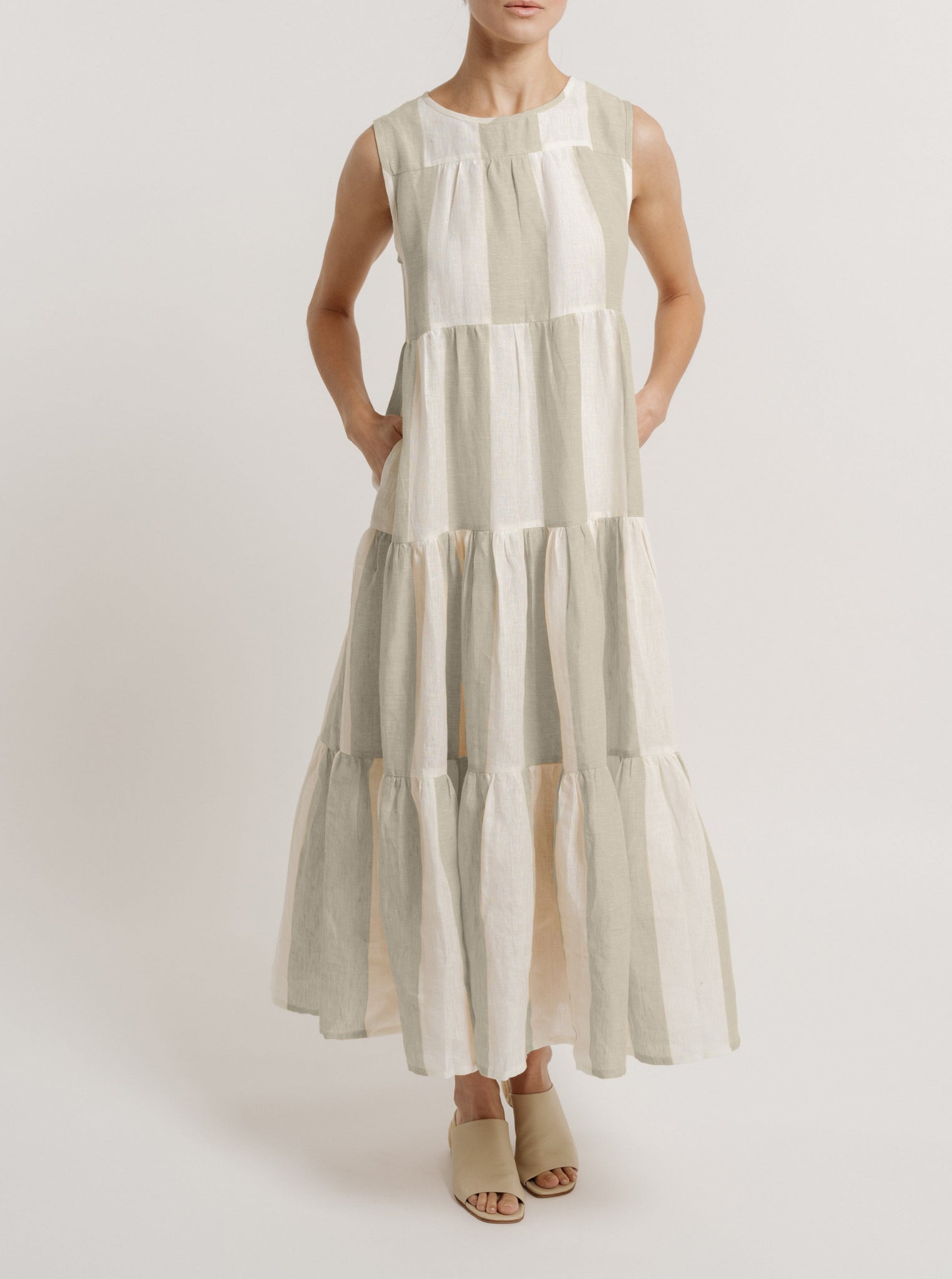 A woman wearing a sleeveless, white and grey Tiered Linen Maxi Dress - Tulum Stripe.