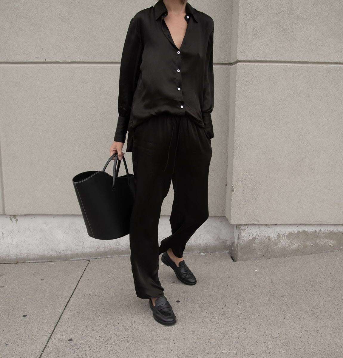 A woman wearing the Leonie Pant - Black made from Bemberg Cupro fabric while lounging.
