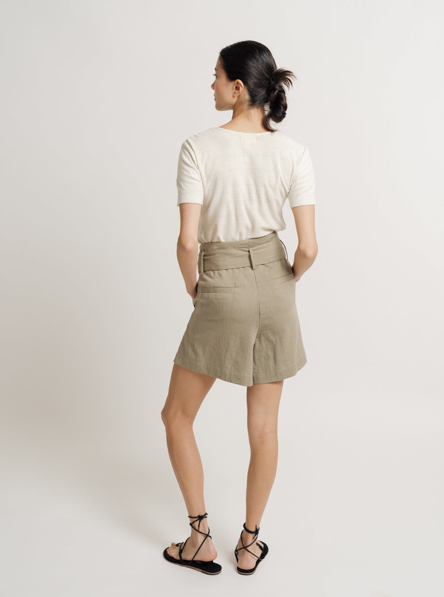 The back view of a woman wearing Paper Bag Shorts made of cotton sateen.