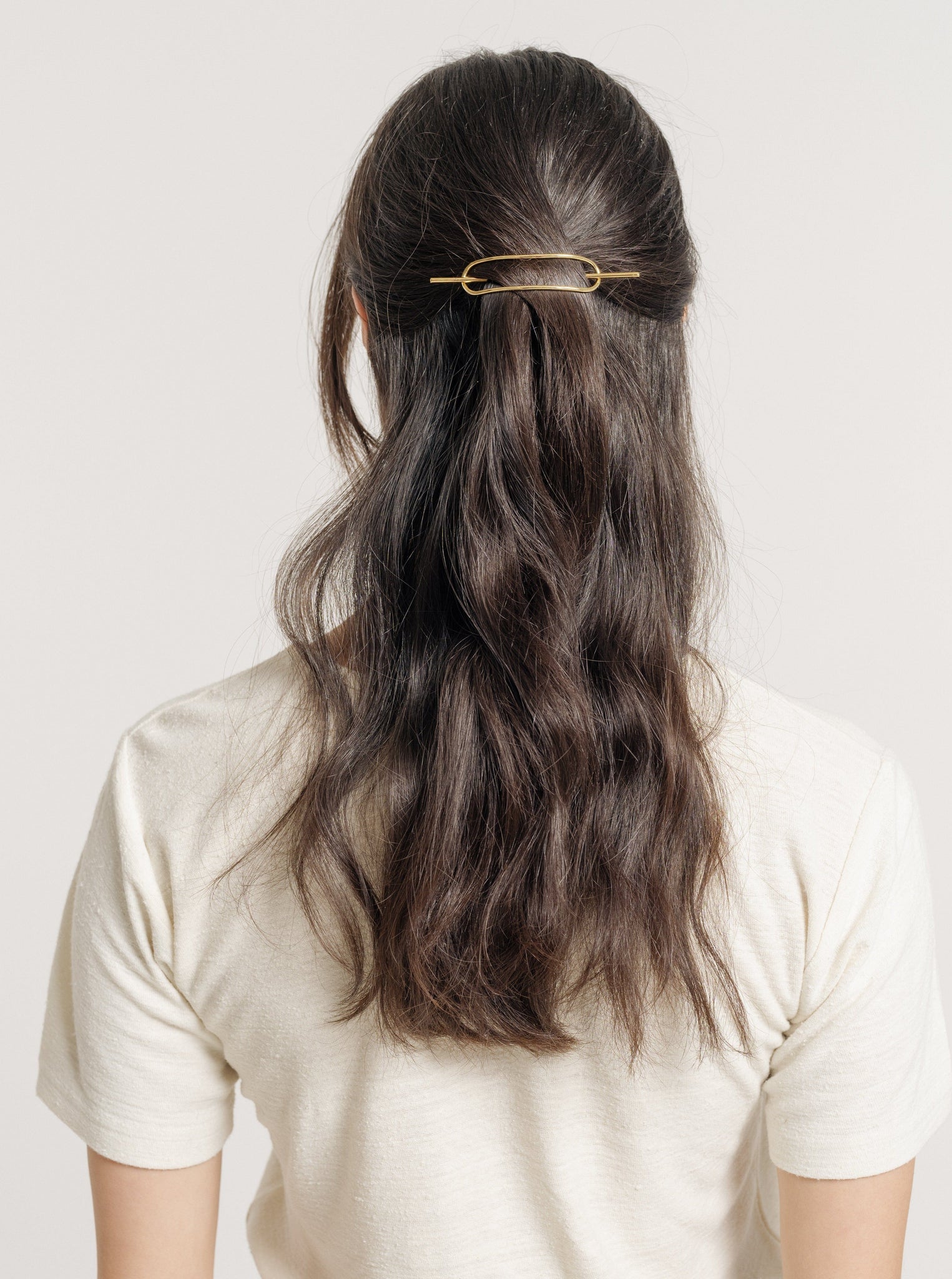 The back view of a woman wearing a Petite Oval Hair Pin in a half-up style.