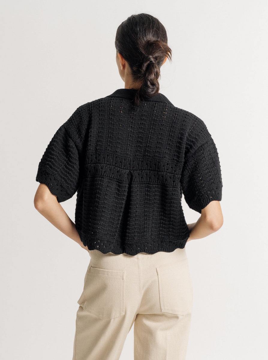 The back view of a woman wearing the Roma Crochet Top - Black - Pre-order and beige pants.