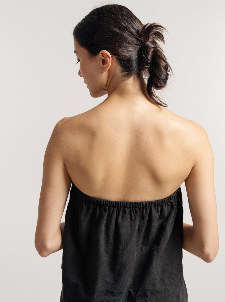The back view of a woman wearing a black Cross Back Tank - Black Silk Noil - Pre-order.