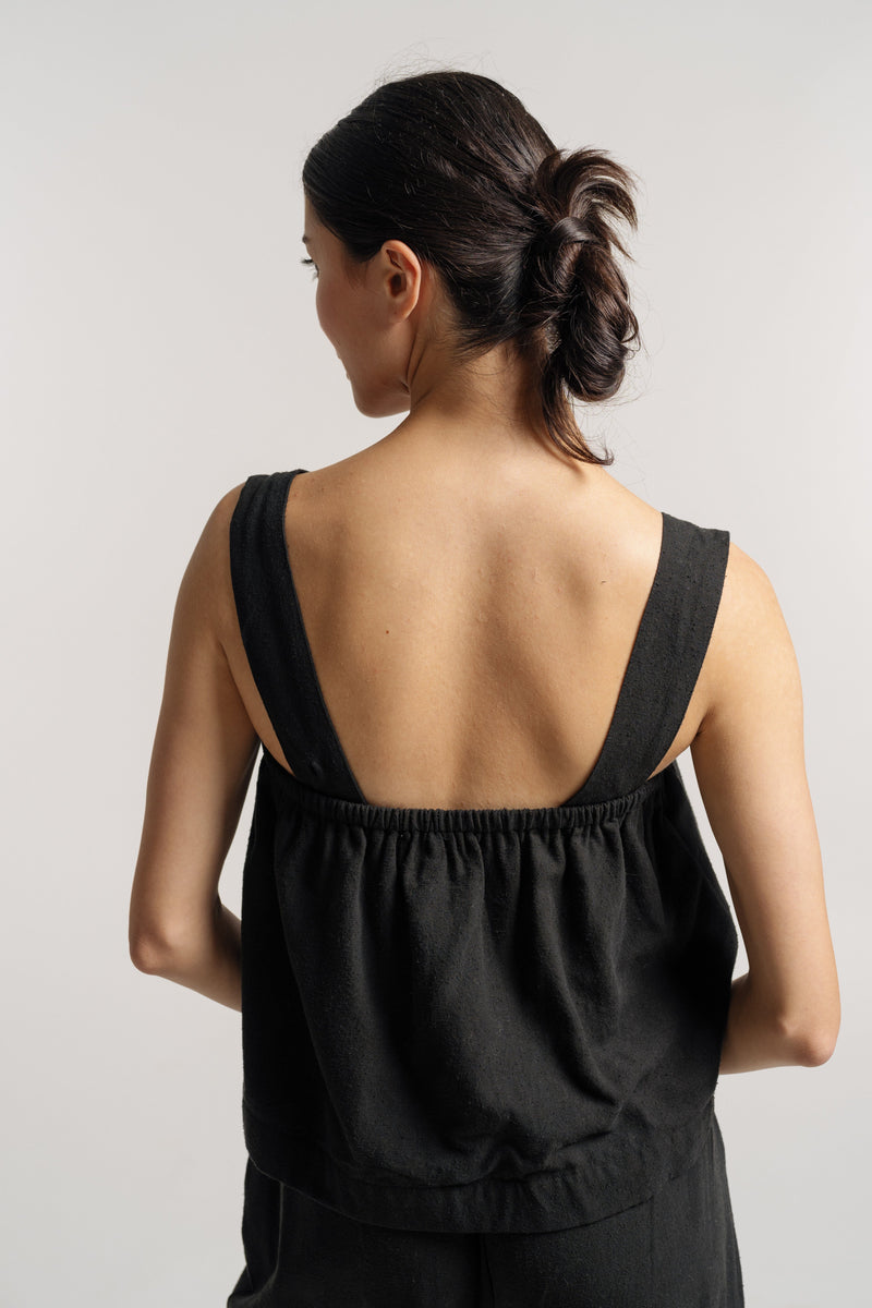 The Cross Back Tank - Black Silk Noil - Pre-order offers ease and style for warmer days. Perfect for resort pre-orders, this black top enhances the back view of any woman.