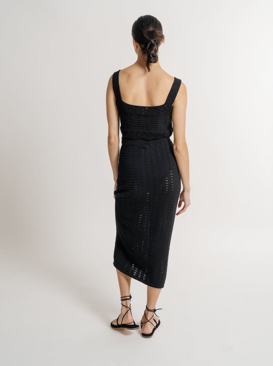 The back view of a woman wearing a Straight Knit Skirt - Black with an elasticated waistband.