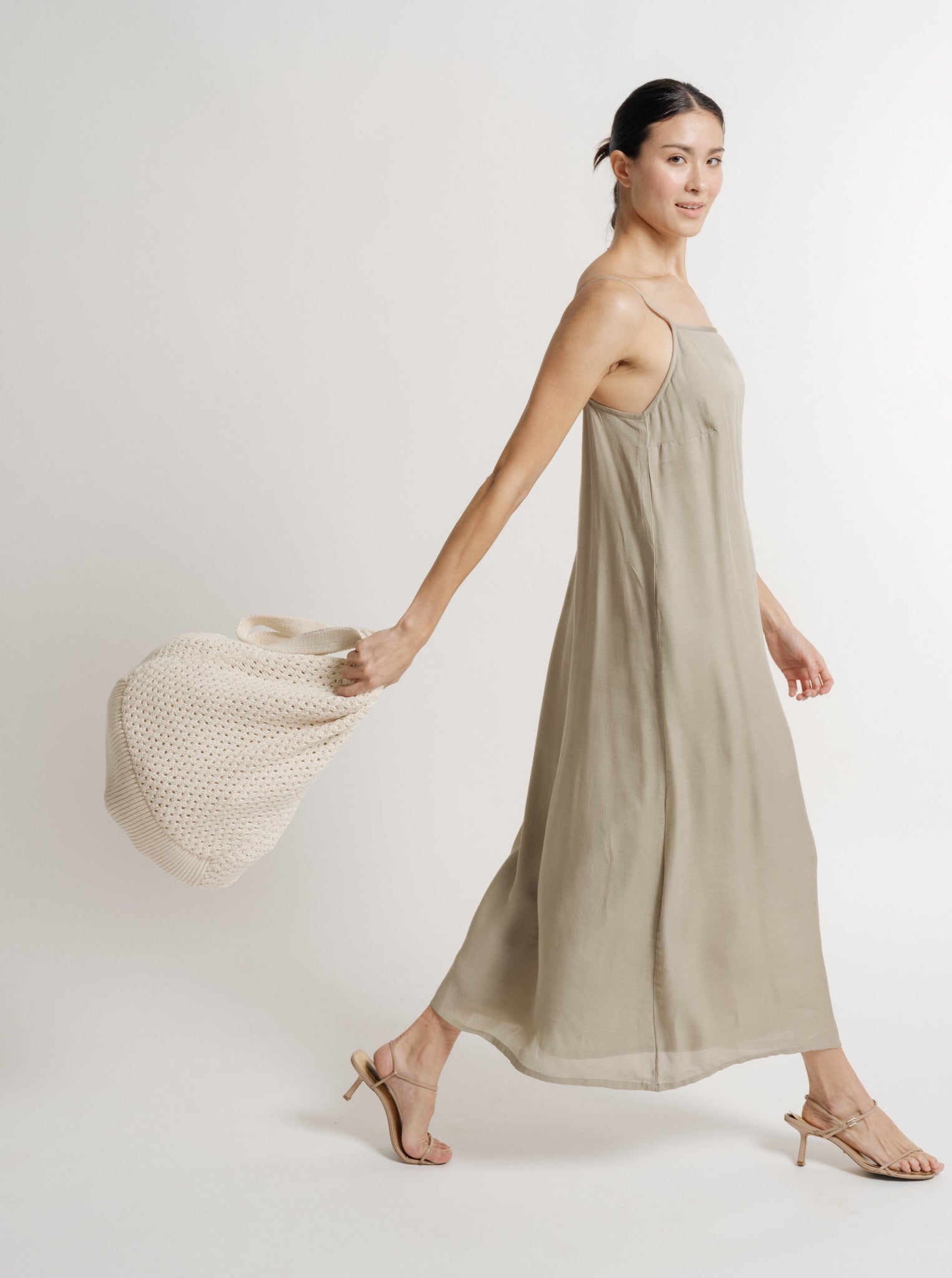 The model is wearing a sage green Bemberg Cupro Crepe dress and carrying a 90's Maxi Slip Dress - Putty - Pre-order bag, available for resort pre-orders.