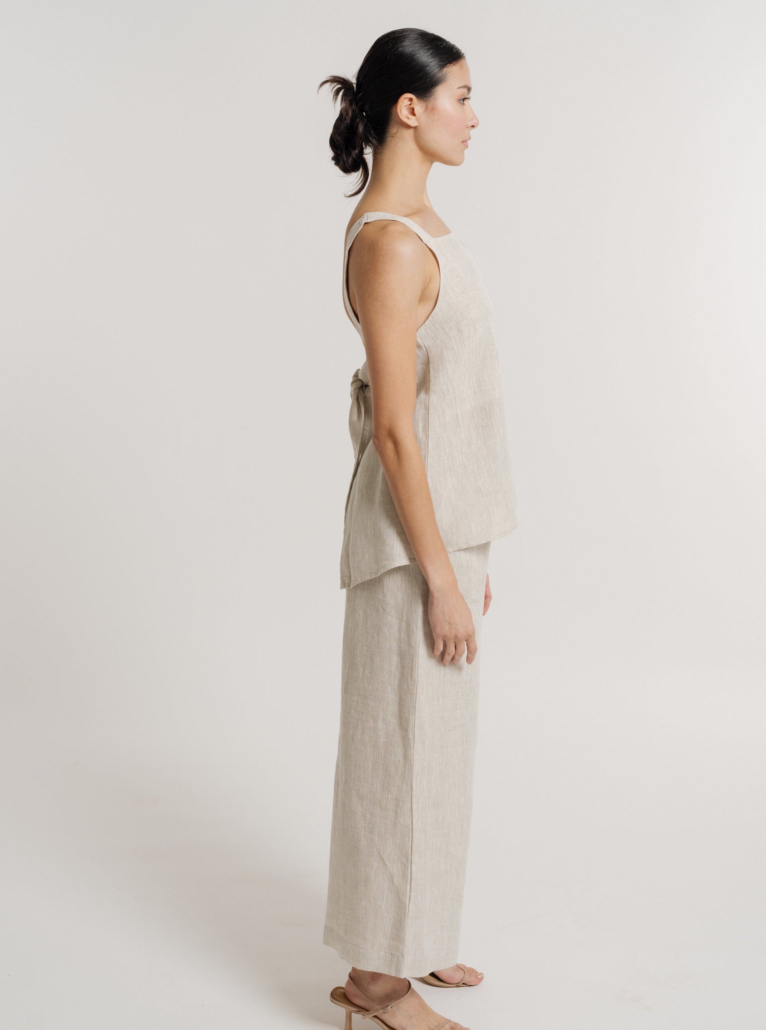 The back view of a woman wearing a Tie Back Linen Tank - Natural.