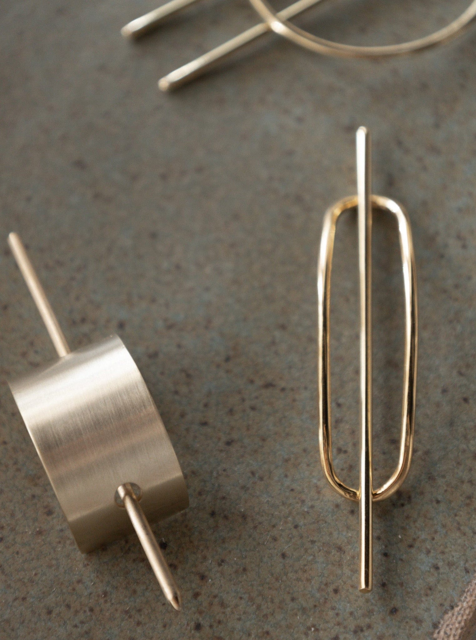 A pair of gold plated earrings with a Brushed Arch Hair Pin design on a table.