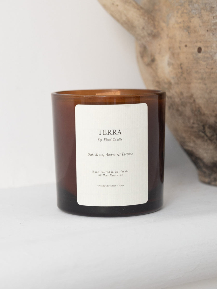 A hand-poured candle with the word Tira on it, featuring a Terra scent.