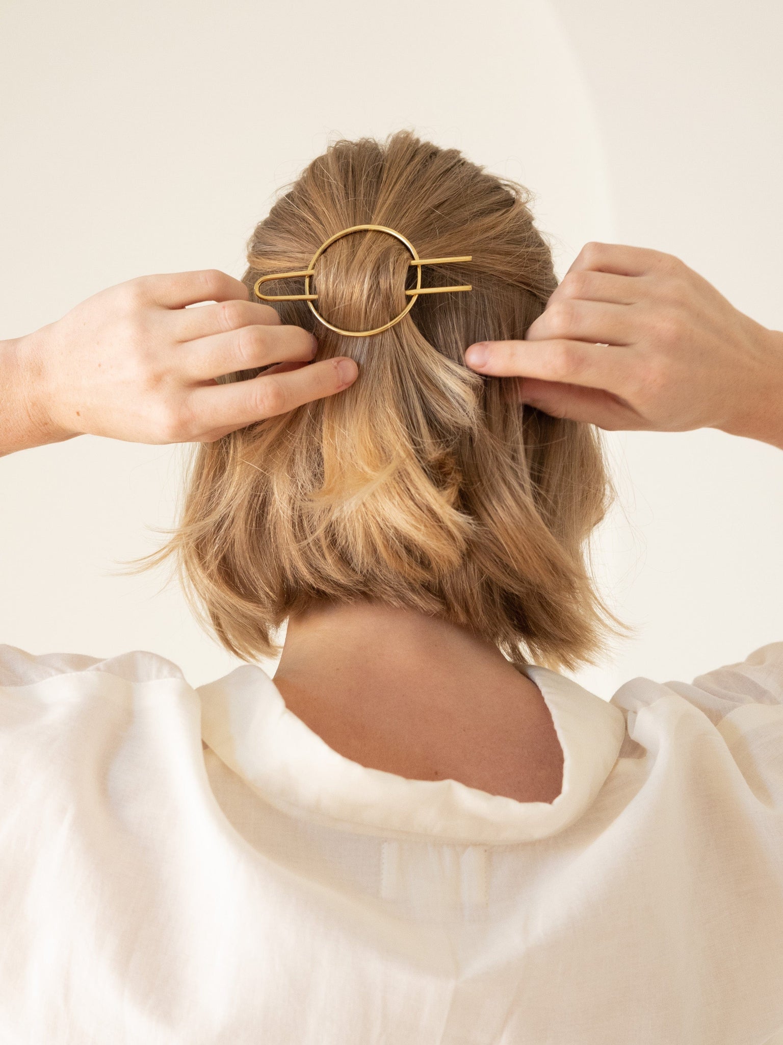 A woman is holding a Classic Hair Pin - pre-order in her hair.