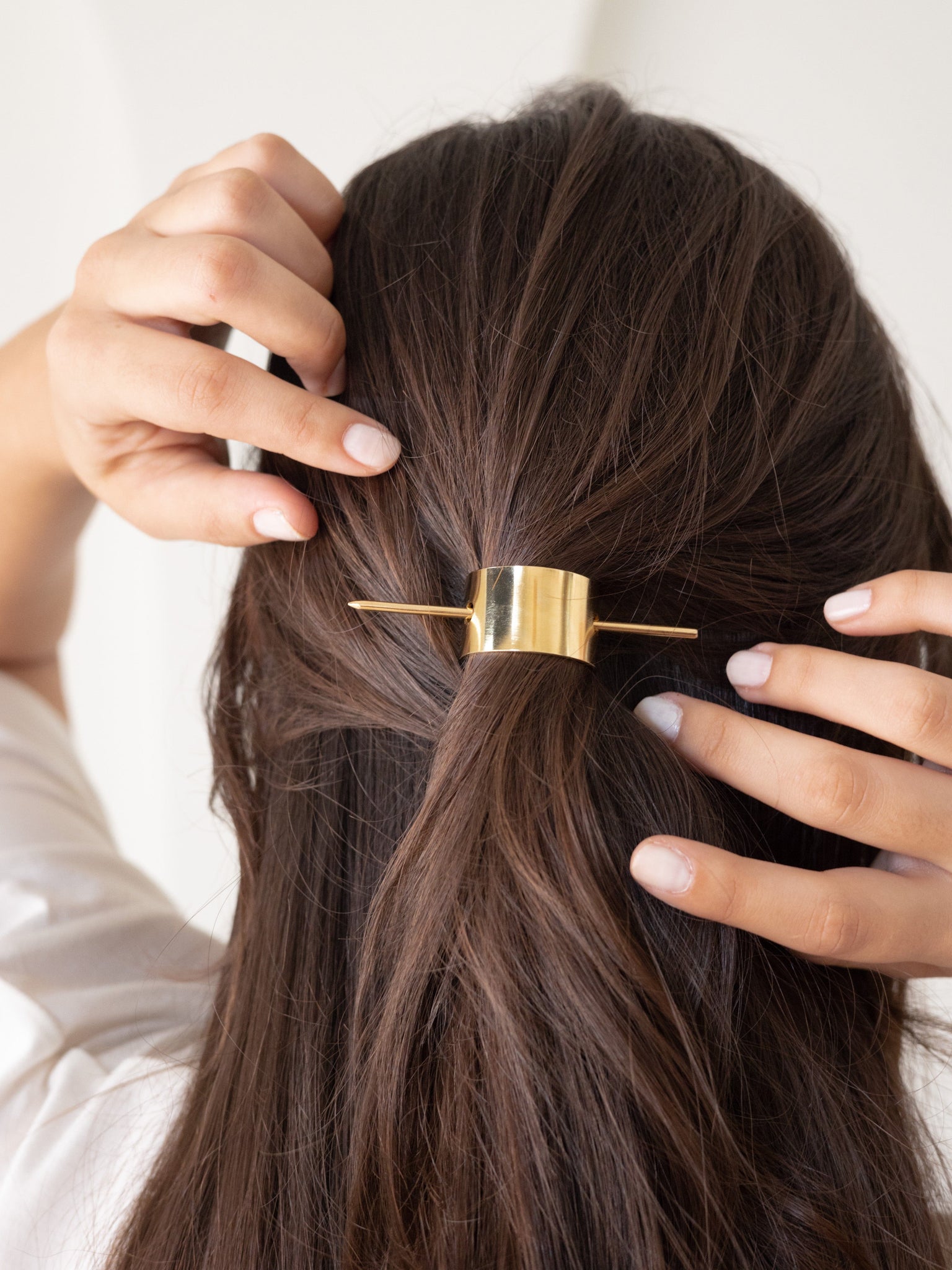 A woman is combing her hair with a Brushed Arch Hair Pin.
