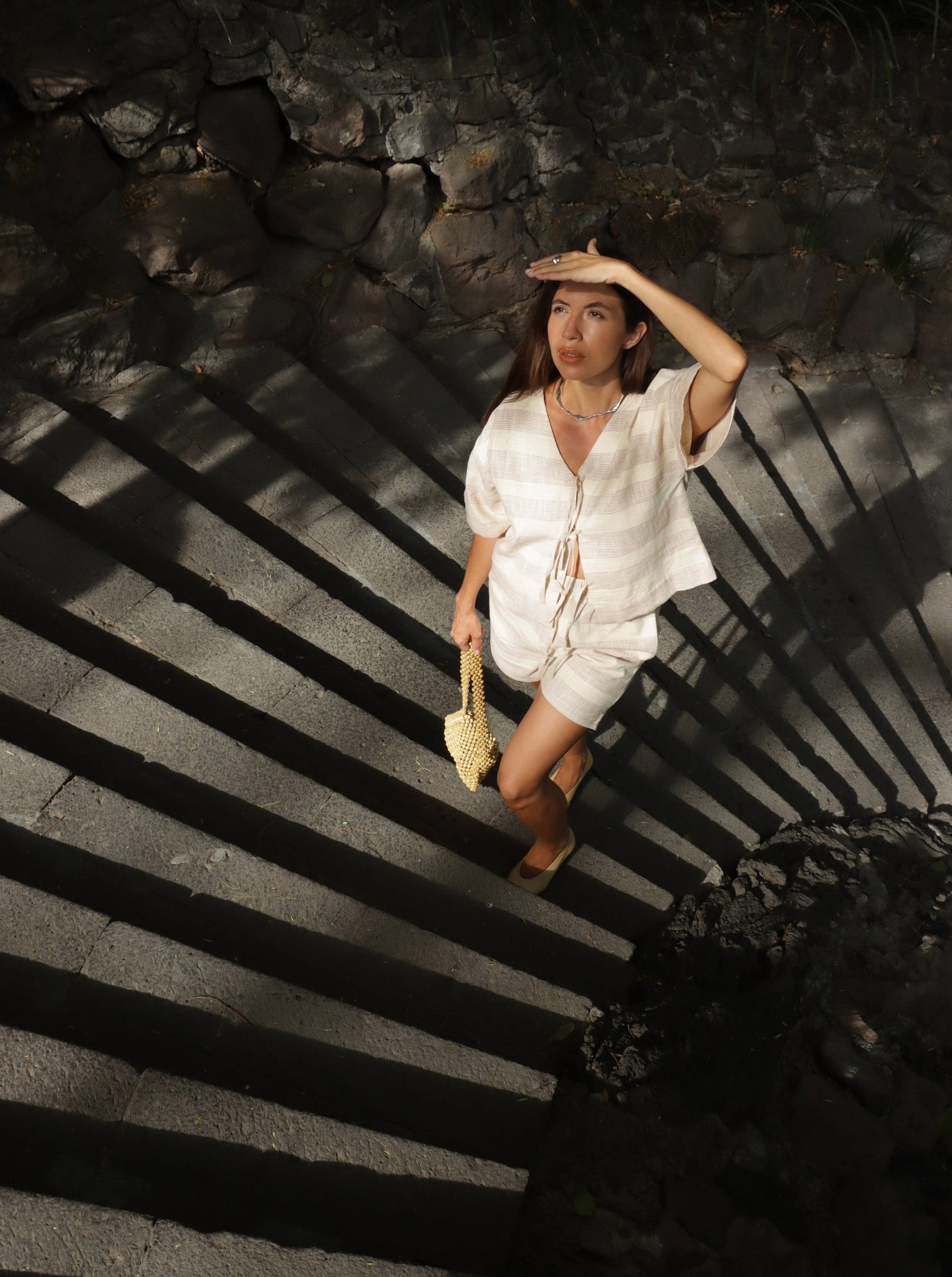 A woman walking down a set of stairs wearing the Baker Top - Terracotta Ticking Stripe.