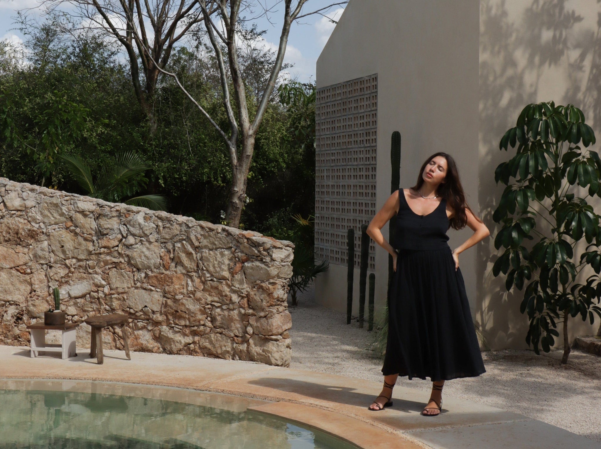 A woman in a Full Midi Skirt - Ink Plaid dress standing next to a pool.