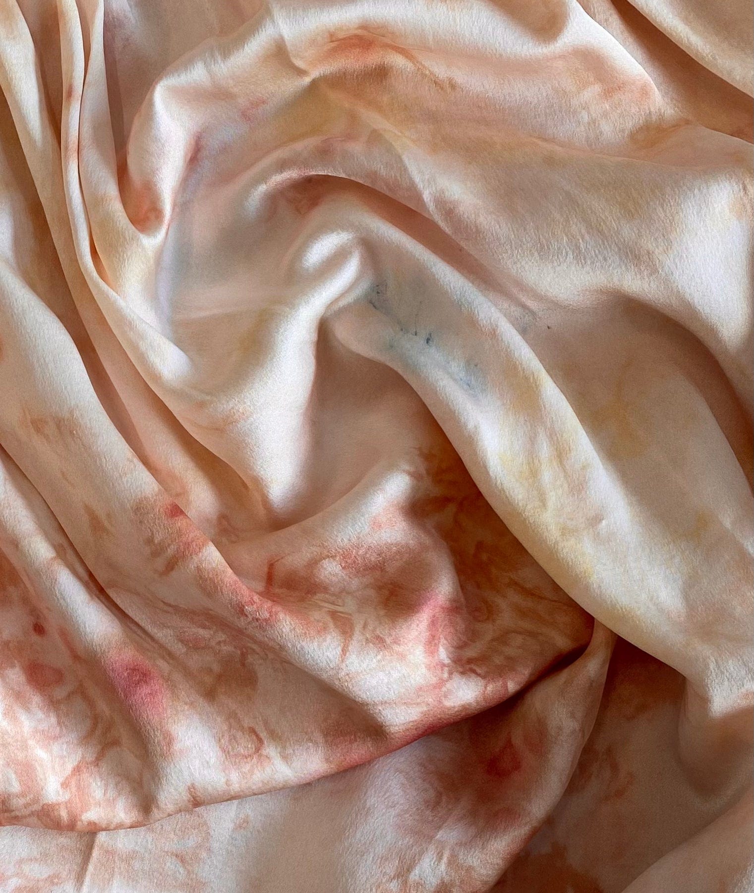Close-up of gently wrinkled peach-colored 100% Silk Midi Slip Dress - Botanical Ice Dye fabric with subtle texture variations.