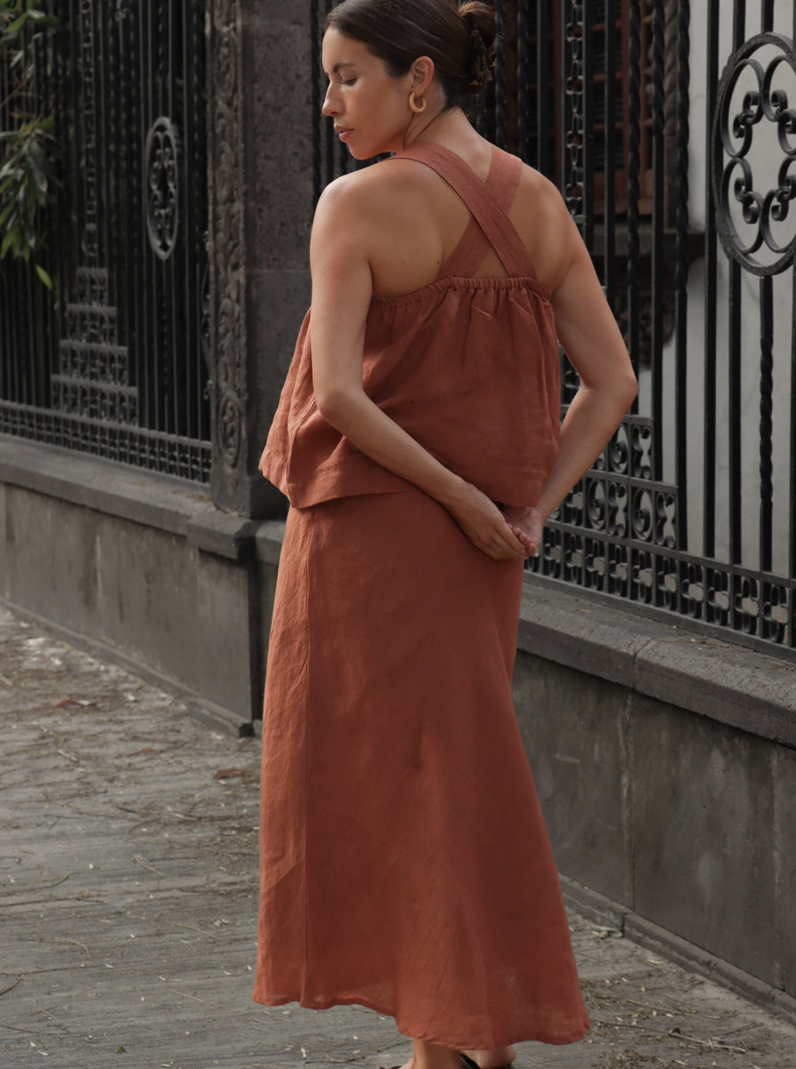 A woman in a Jardín Midi Skirt - Amber Brown - Sample is walking down the street.