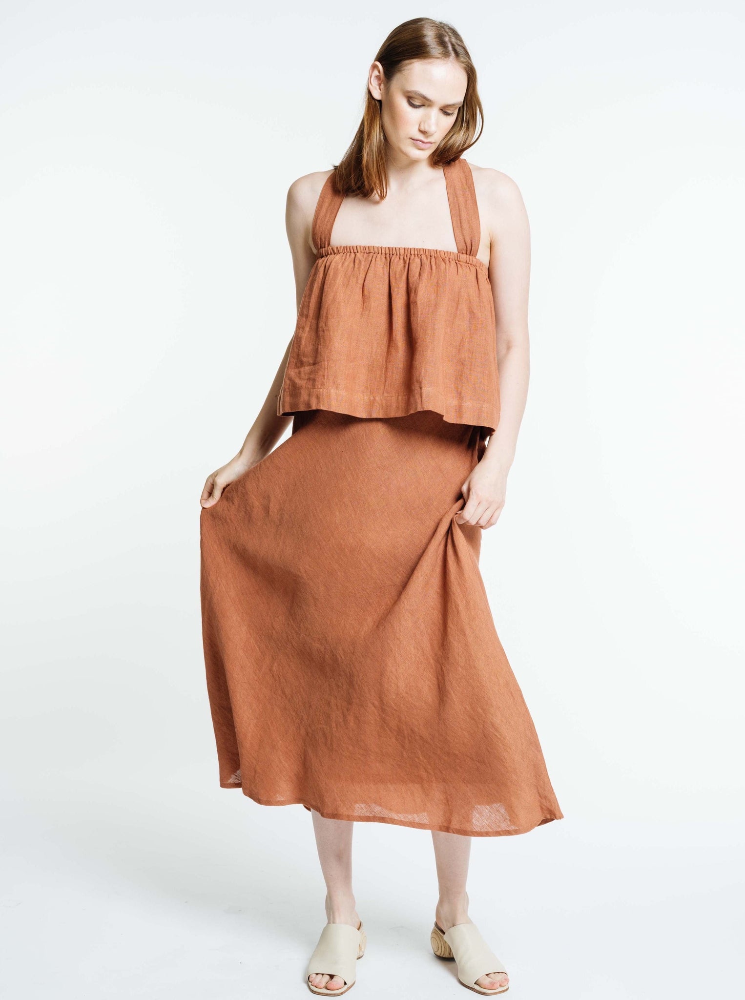 The model is wearing a Jardín Midi Skirt in Amber Brown.
