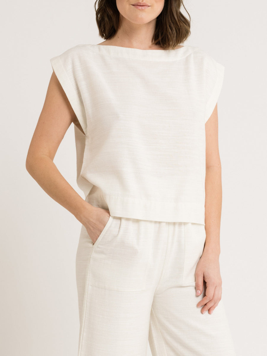 A model wearing the Everyday Top - Ivory, a wide neckline white top made of cotton fabric.