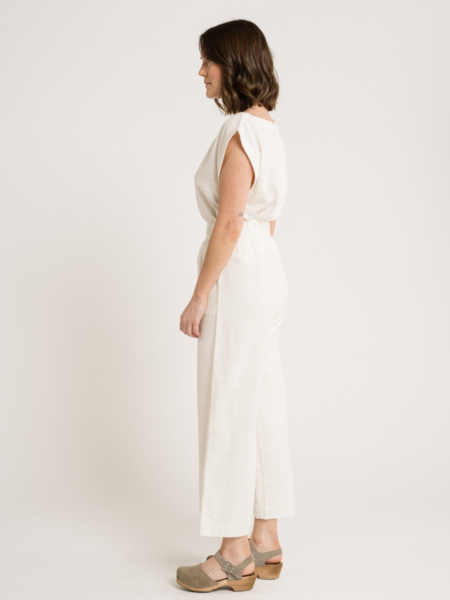 The back view of a woman wearing the Everyday Crop Pant - Ivory.