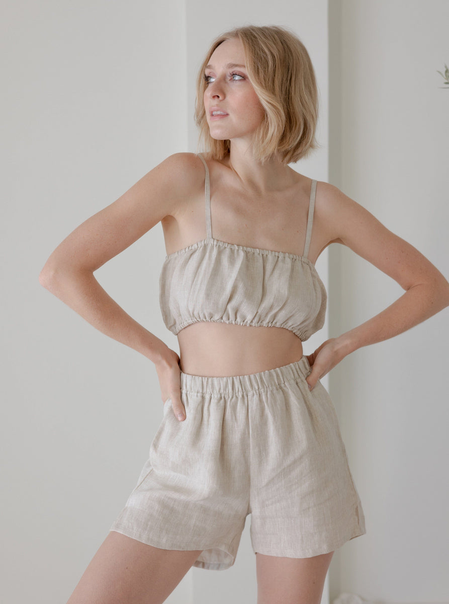 The model is wearing an Elastic Bandeau - Natural - Sample crop top and shorts.