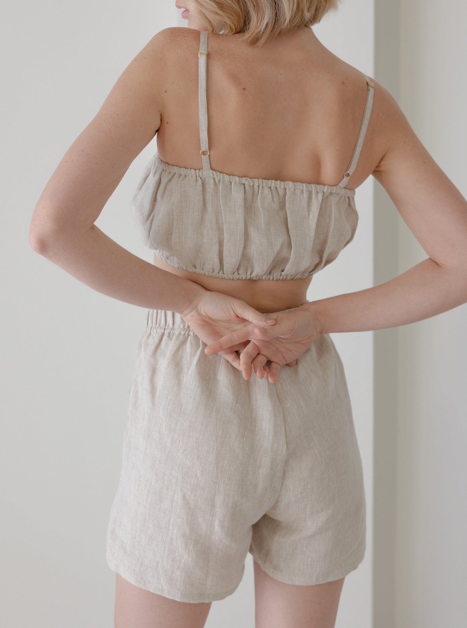 The back view of a woman wearing an Elastic Bandeau - Natural - Sample linen top.