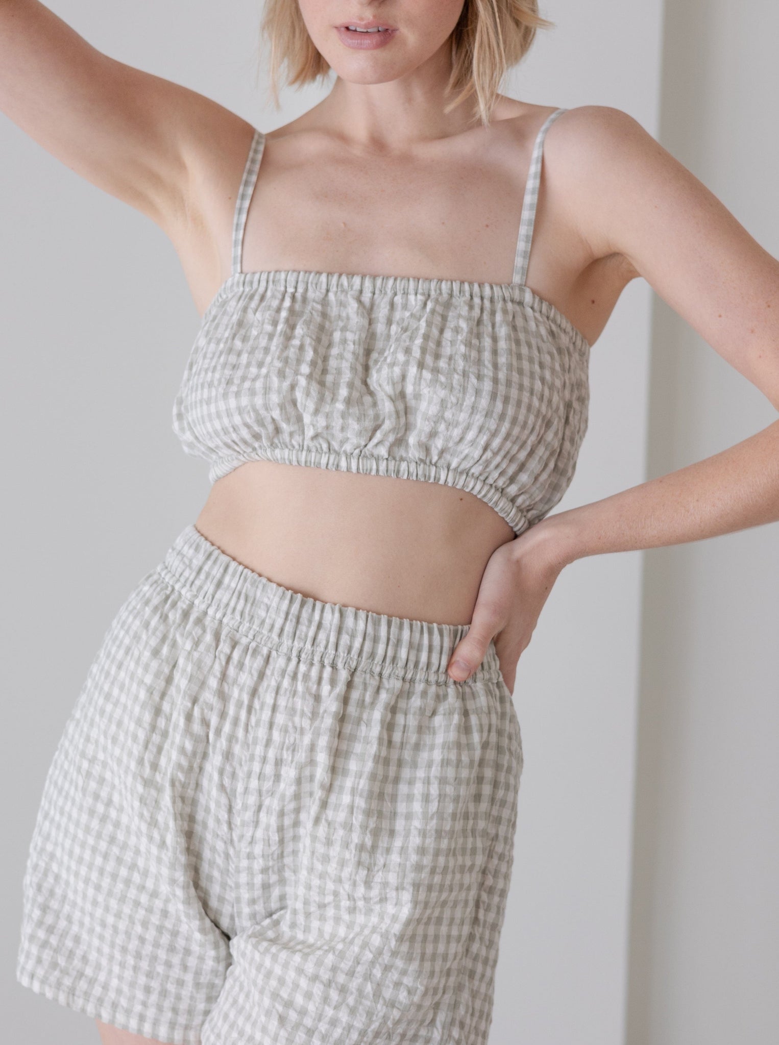 The model is wearing a hand Elastic Bandeau - Sky Gray Gingham - Sample top and shorts made from organic cotton.