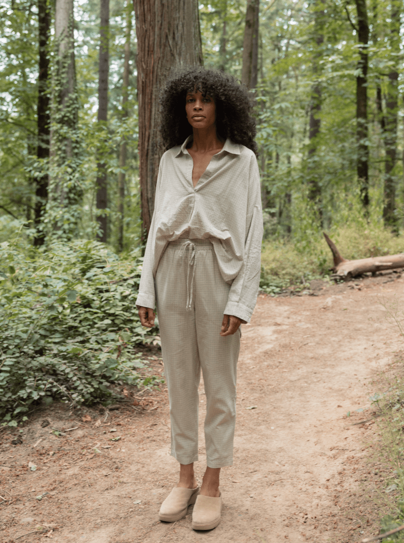 A black woman standing in the woods wearing Harem Pants - Dove Small Grid - Sample made from organic cotton.