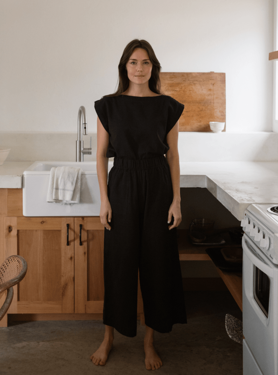 A woman standing in a kitchen wearing Everyday Crop Pant - Black.
