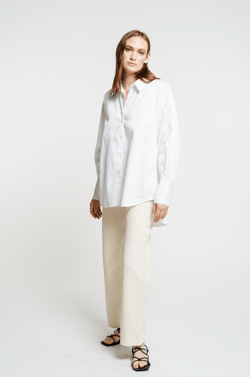 The model is wearing a Museo Button Up - White shirt and beige trousers.