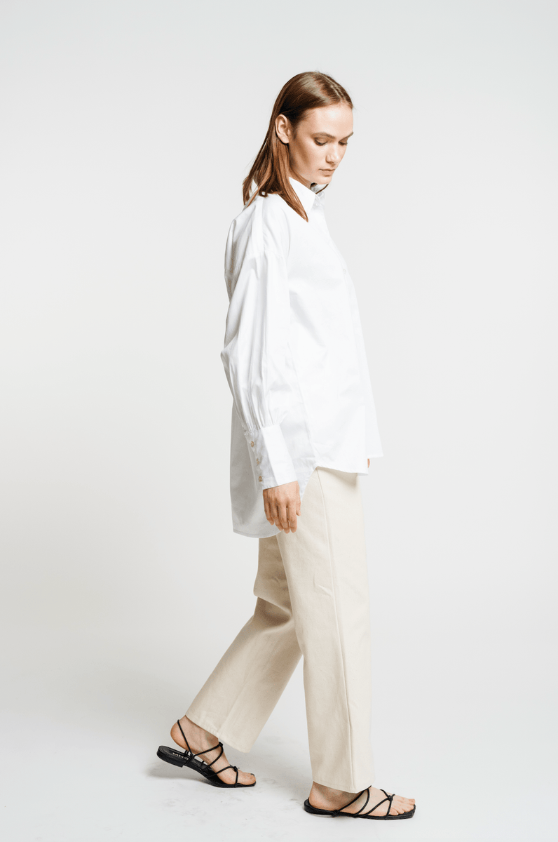 The model is wearing a Museo Button Up - White shirt and tan sandals.