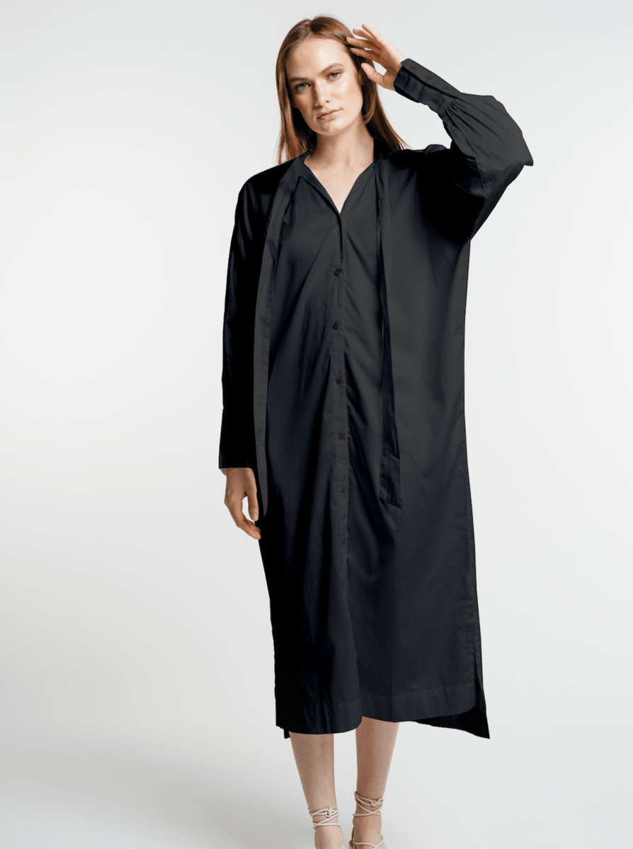 The model is wearing a black shirt dress made of organic cotton.
